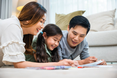 Asian family lying on floor painting with little child daughter in living room, Happy Father Mother and daughter drawing together on paper at home, Loving family activity enjoyの写真素材