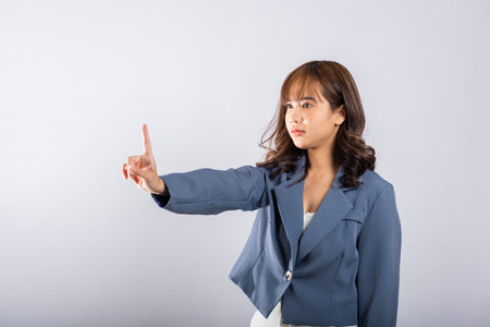 Portrait Asian confident young business woman wearing a suit showing one finger for stop gesture studio short isolated on white background, female telling to stop in disapproval prohibit somethingの写真素材