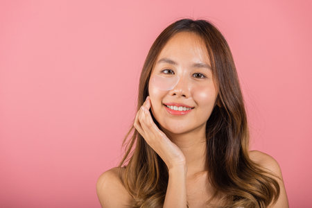 Eye skin treatment. Asian beautiful young woman smiling mask cosmetic patches gel under the eyes, Portrait female with natural makeup hydrogel eye patch on face, isolated on pink background, skincareの写真素材