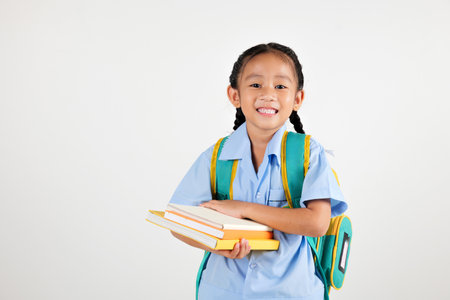 Portrait Asian smiling young girl kids kindergarten hair in pigtails holding backpack hold books...
