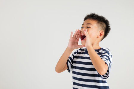 Asian happy portrait cute young kid boy standing hand on mouth talking news announcement studio shot...