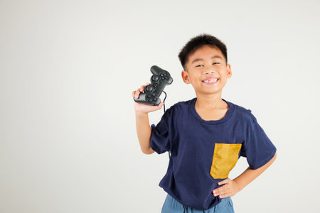 Asian happy portrait young kid boy smile lifestyle games technology holding joystick game playing on hands studio shot isolated on white background with copy space, primary children relaxation timeの写真素材