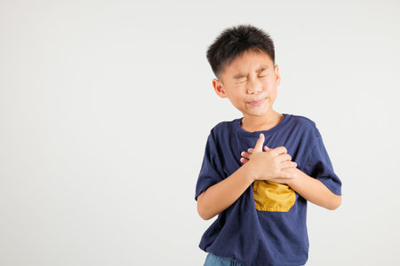 Young kid boy pressing on chest pain isolated on white background, painful expression heartache, primary children having heart attack heart disease, Painful cramps problemの写真素材