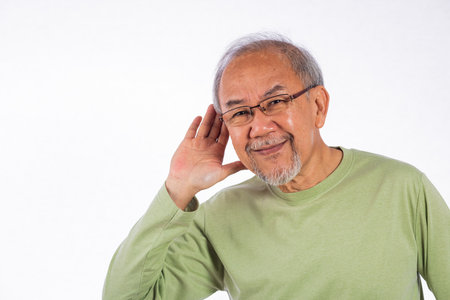 Portrait Asian old man with glasses and a beard listening to sound something, possibly engaged in...