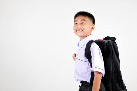 Portrait smile Asian little boy primary posing with schoolbag phone studio shot isolated white background, happy cute man kid wear school uniform and backpack learn new things, back to school conceptの写真素材
