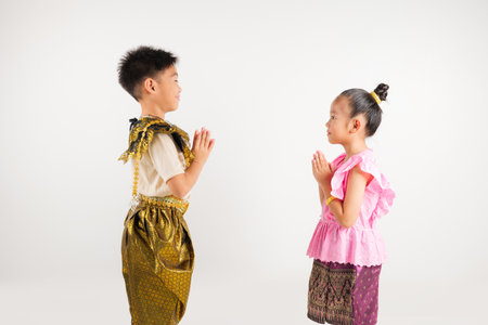 Portrait Thailand kid boy and girl smiling traditional Thai dress costume posing to pay respect in studio isolated white background, Happy primary and kindergarten children sawasdee symbol or welcomeの写真素材