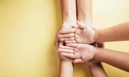 Expressing support and togetherness, Studio shot presents a top view of family hands stacked on an isolated background. Parents and children hold an empty space for Family and Parents Day.の写真素材