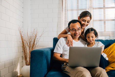 Modern family time on the couch parents and kids with a laptop. A young man woman son and daughter find happiness in their togetherness education and online connections.の写真素材