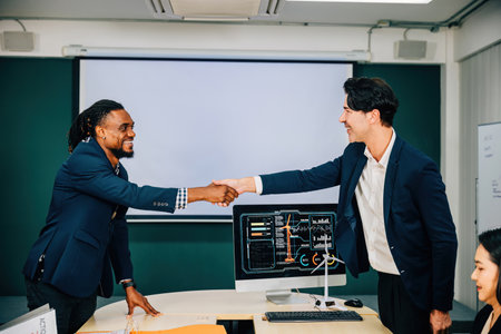 A cheerful young manager and a new employee shaking hands in a successful business partnership meeting. Close-up of the handshake in the office, symbolizing collaboration and teamwork.の写真素材