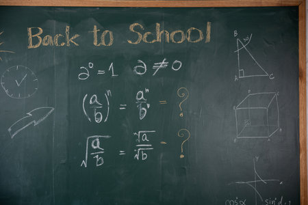 A chalkboard with math problems and the words back to school written on it. The chalkboard is green...