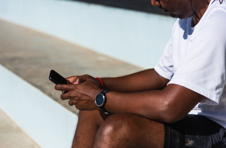 Close up Asian young athlete sport runner black man wear modern time smart watch and sync to a smartphone check running result after training run at the outdoor, healthy exercise workout technologyの写真素材