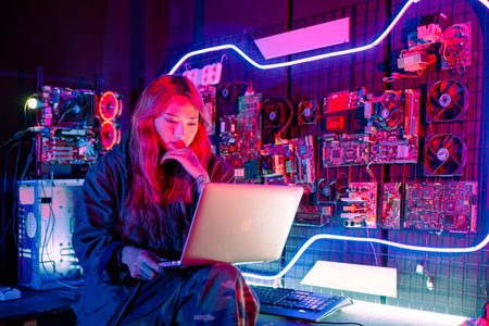 Asian woman is sitting at a desk with a laptop service in server room, Thinking and solve problems, Software engineer typing coding in laptop computer at data center, Cyber securityの写真素材