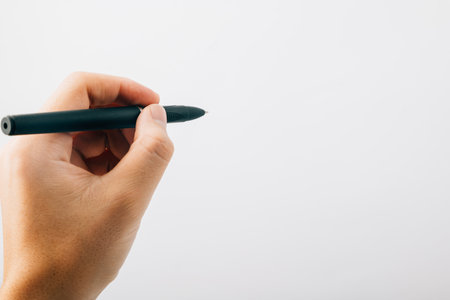 A person hand is holding a pen and writing on a white background. Concept of creativity and the act...