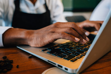 Focused on his laptop in a modern roastery office the owner and barista ensures top-quality beans. Using technology and equipment meticulous checking is key. Business meets quality standards.の写真素材