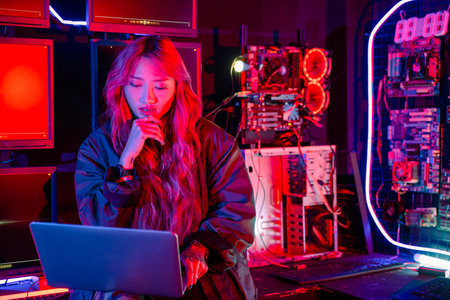 Software engineer typing coding in laptop computer at data center, Hacker woman is sitting at a desk with a laptop service in server room, Thinking and solve problems, Cyber securityの写真素材