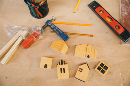 Wooden houses, pencils, and tools on a workbench. Perfect for home construction, DIY projects, and handmade woodwork. Carpentry tools for crafting at home workshopの写真素材