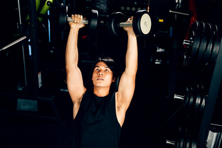 Asian man muscular lifting dumbbell on bench in fitness gym, Happy young men doing strength training...