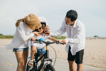 Sunset serenity on sandy beach, cheerful family enjoys summer road trip teaching and learning bicycle riding. Laughter safety helmets and carefree smiles define this perfect vacation moment.の写真素材