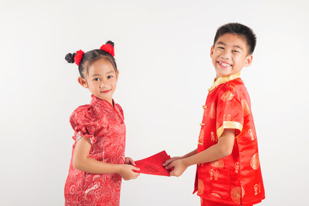 Chinese New Year. Happy Asian little kid sibling boy and girl wear red cheongsam qipao giving red hongbao envelope packet monetary gift for lucky moneyの写真素材