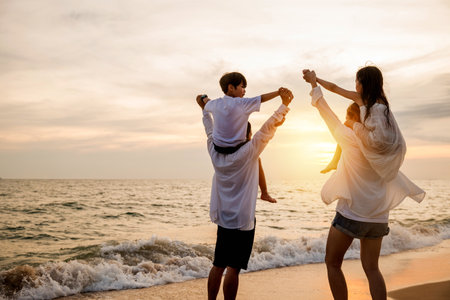 Happy family day. Parents carrying children on shoulders at the beach on sunset time, Father, Mother and kids playing together outdoors on summer beach, Family on holiday summer vacation travelの写真素材