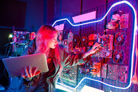 Cyber security. Software engineer holding laptop computer at data center checking hardware, service in server room, check circuit board with many small componentsの写真素材