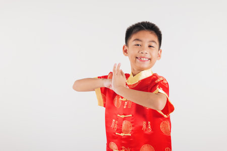 Happy Chinese New Year Smiling Asian boy in a traditional red cheongsam dress makes a congratulatory gesture, symbolizing blessings and good fortune. festive themes. Isolated on white backgroundの写真素材