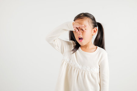 Asian young child unhappy about smell, disgust expression squeezing nose with fingers. Kid girl in kindergarten has something that stinks, bad smell situation, studio shot isolated on white backgroundの写真素材