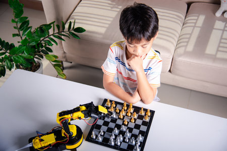 Asian little boy thinking and wait robot arm playing chess, STEM education E-learning, Funny children learning successful getting a lesson control robot arm game, Technology science education conceptの写真素材