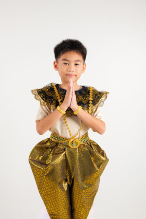 Portrait of Thailand kid boy smiling traditional Thai dress costume posing to pay respect in studio shot isolated on white background, Happy primary child sawasdee symbol or welcome expressionの写真素材