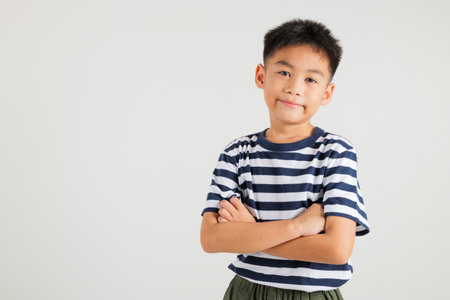 Asian happy portrait cute young kid boy smiling confidence with arms crossed studio shot isolated on white background and copy space, primary children person lifestyle arm foldedの写真素材