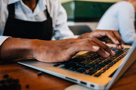 Coffee business owner and barista in a modern office using laptop and machinery to check bean...