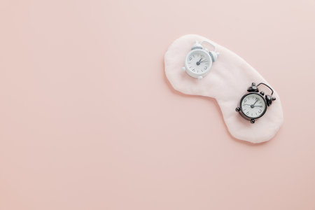 World Sleep Day essentials, eye mask and clock on pink. Focused on Sleep Day awareness and the importance of health care and restful nights.の写真素材