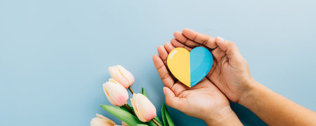 Down Syndrome Day features hands holding a yellow and blue heart. Raising awareness for Down Syndrome and Autism Awareness globally on a vibrant blue background.の写真素材