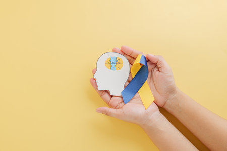 Down Syndrome Day concept with hands holding a head featuring puzzle pieces and a ribbon. Supporting global awareness for Down Syndrome and Autism Awareness.の写真素材