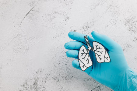 Doctor hands wearing gloves hold lungs paper for World TB Day. Promoting awareness of lungs health, tuberculosis prevention, and respiratory care globally.の写真素材