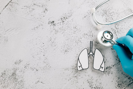 World TB Day with a doctor gloved hand checking lungs paper and stethoscope. Highlighting lungs health, tuberculosis awareness, and respiratory medical care on a gray background.の写真素材