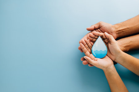 World Water Day concept. Two pairs of hands hold a water drop on blue background, promoting care, clean hygiene, and CSR efforts to save water for a sustainable world and every precious drop of life.の写真素材