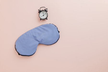 Stylish sleep eye mask and alarm clock on pink background for Sleep Day. Highlighting World Sleep Day awareness and the importance of health and care. Flat lay, top view with copy spaceの写真素材