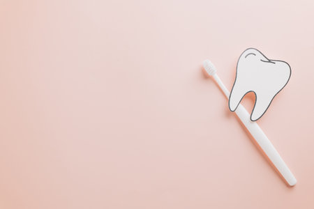 Tooth paper cut and toothbrush on pastel pink for Dentist Day. Emphasizing dental care, oral health, and teeth hygiene with stylish flat lay imagery for World Dentist Day.の写真素材