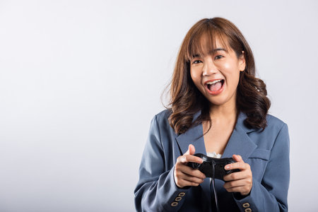 Asian happy portrait beautiful business woman wearing a suit smile lifestyle games technology her holding joystick game playing on hands on white background with copy space for text, Relaxation timeの写真素材