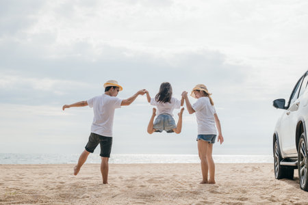 Happy family three hand in hand and jumping on sandy beach, holiday vacations summer road trip, Family day enjoying their time togetherの写真素材