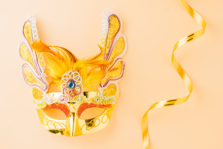 Happy Purim carnival decoration. Golden venetian ball mask isolated on pastel background with copy space, Jewish Purim or Mardi Gras in Hebrew, celebration holiday background banner designの写真素材