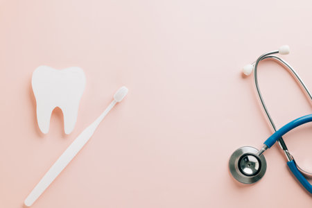 World Dentist Day concept: tooth cutout and stethoscope on pink. Focused on dental health, orthodontics, and oral hygiene with a pastel mockup perfect for postcards and health campaigns.の写真素材