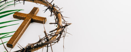 Wooden cross, crown of thorns, and palm leaves on white background for Palm Sunday. A symbol of faith, sacrifice, and Sunday reflection.の写真素材