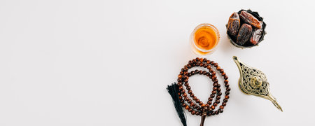 Ramadan Day. Dates with prayer beads and tea in a bowl on a white background for Ramadan. An overhead arrangement highlighting a holy Islamic celebration and the unity of Muslim faith.の写真素材
