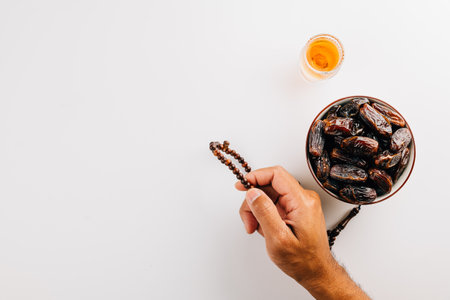 Ramadan scene, hand holding beads, tea, and dates on a white backdrop. Perfect for celebrating this Islamic festival with thoughtful decoration. Ramadan celebrationの写真素材