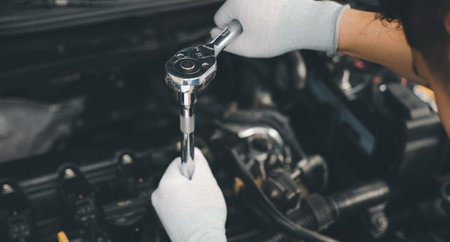 Service outdoor. Close up hands of auto mechanic man working on car engine using wrench to repair...