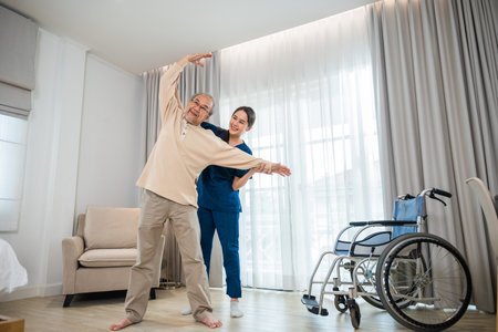 Old senior man enjoys training with physiotherapist for outstretched arms at home, Asian physical therapist patient nursing helping elderly exercising arm stretch, Rehabilitation of disabled conceptの写真素材