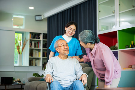 Asian old man on wheelchair with couple and nurse relaxing walking at home, healthcare medical service at nursing home, Happy nurse and wife support retirement senior elderly manの写真素材