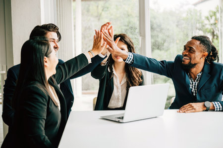 A heartwarming display of cooperation and camaraderie in the office, colleagues celebrate their triumph by exchanging high-fives during a meeting, highlighting the power of unity and support.の写真素材